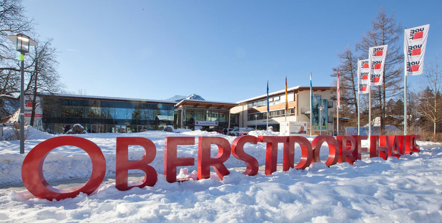 Foto des Oberstdorf Haus von Außen mit Schnee um die Wortmarke "OBERSTDORF" vor den Toren des Hauses zum Baufachkongress - veranstaltet von baumit.